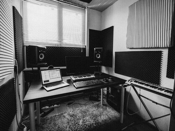Black and white image of home recording studio set u, including keyboards, laptop and speakers.