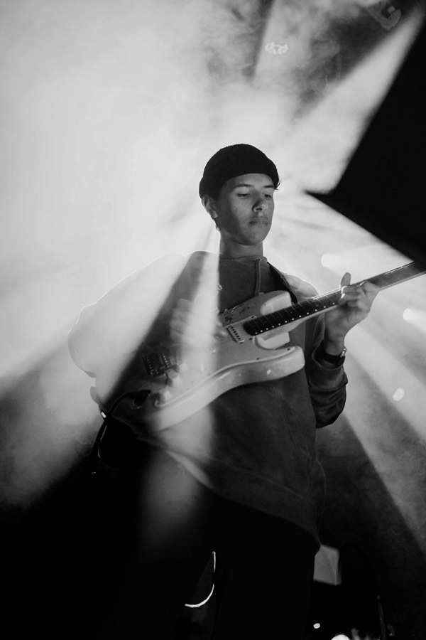 young musician playing electric guitar on stage, photo in black and white