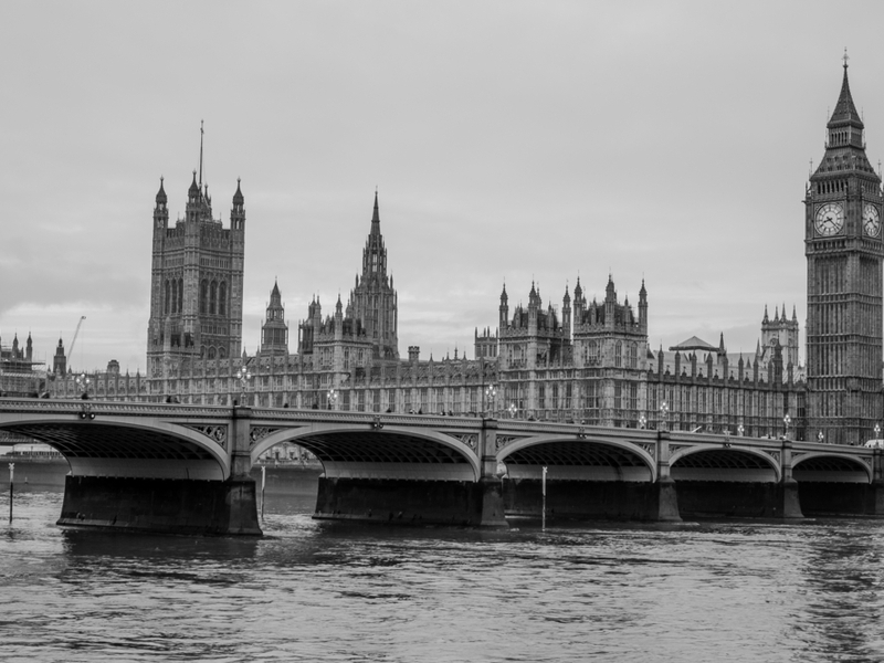 Photo of the Houses of Parliament in London, taken from over the bridge in black and white colours.