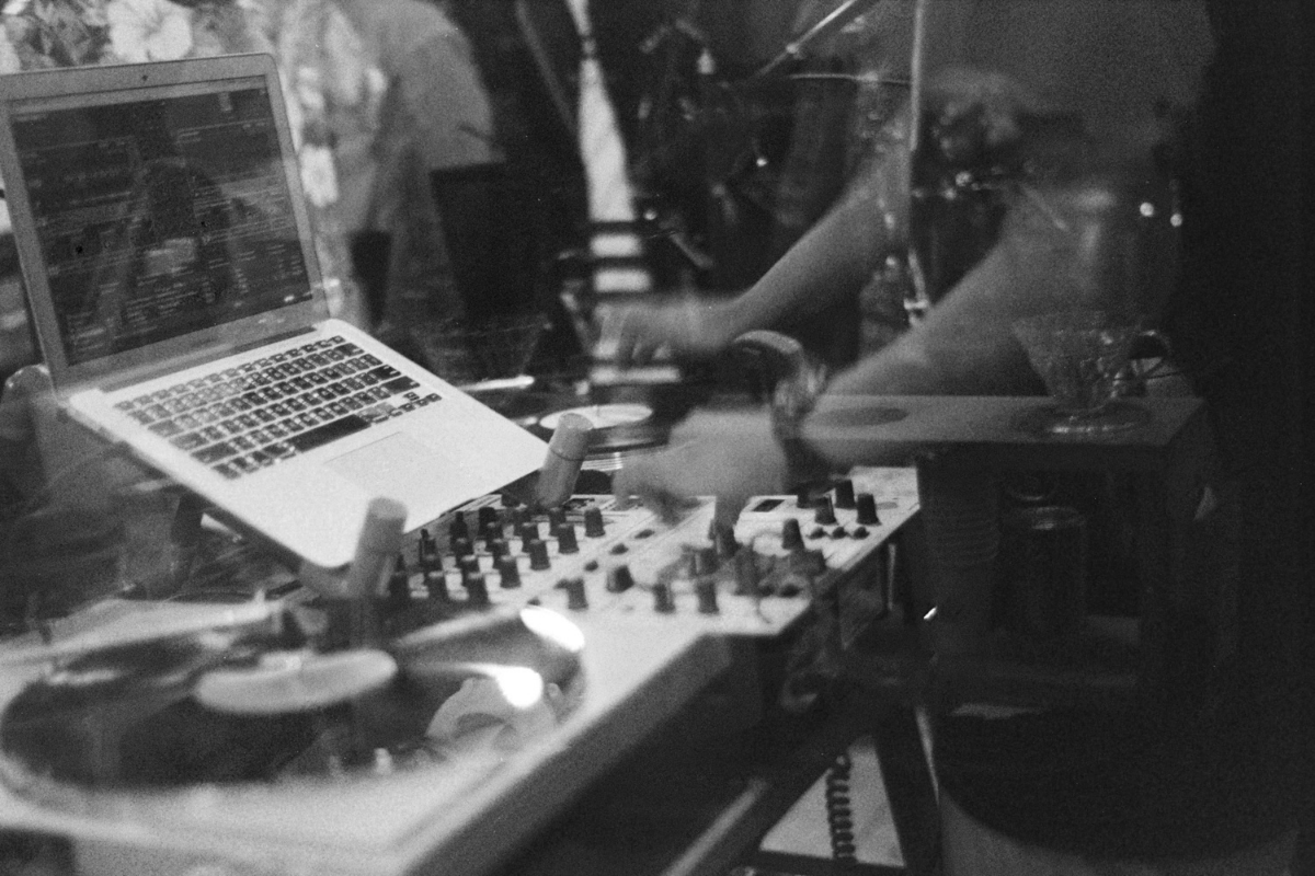 Black and white close up image of mixing desk and open laptop in soft focus.