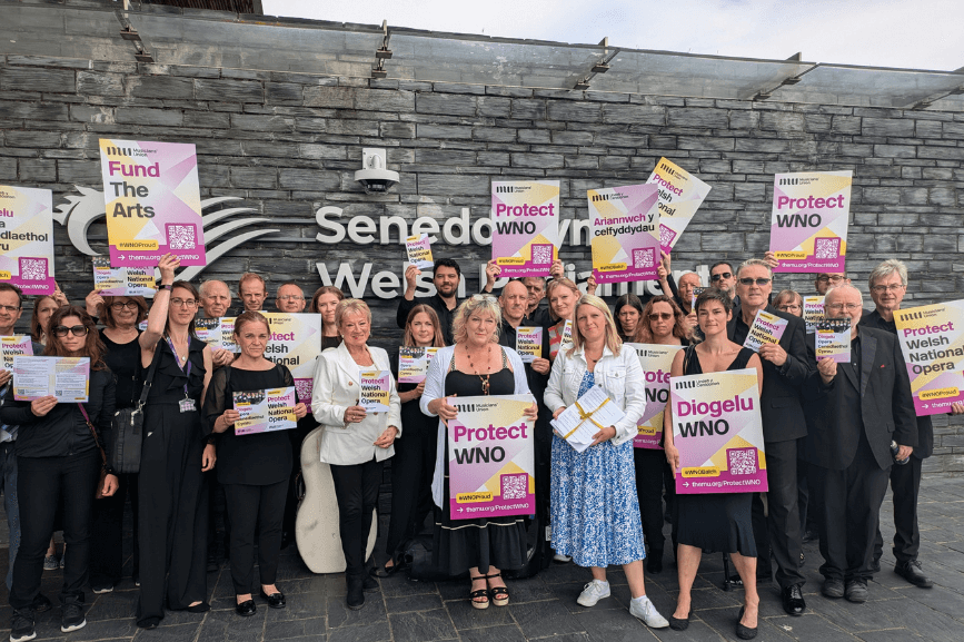 Naomi Pohl standing with members of Welsh National Opera outside the Senedd in Cardiff, holding placards