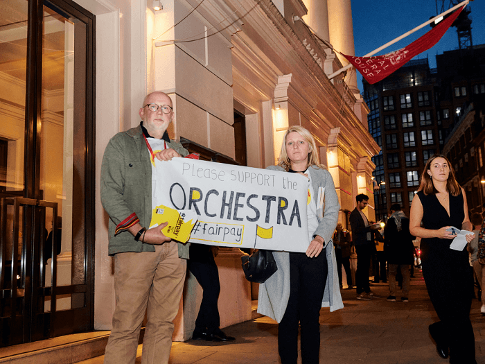 MU General Secretary Naomi Pohl, and MU Head of International Dave Webster hold up a sign outside the Royal Opera House reading 