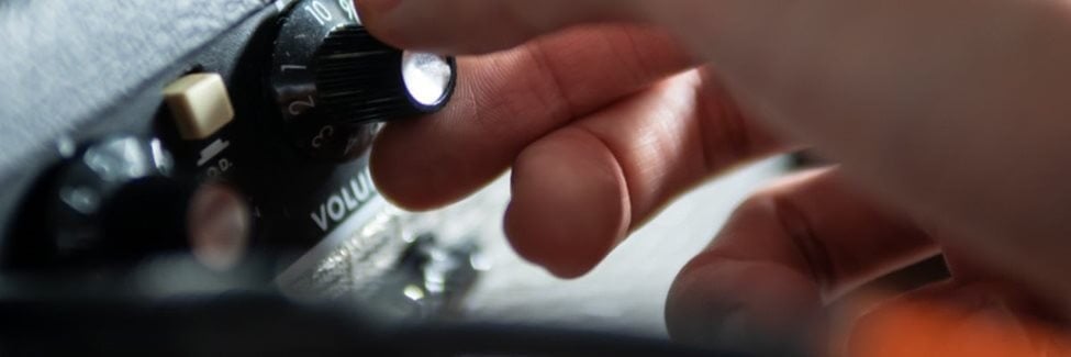 Close up of hand turning the volume button on an amp.