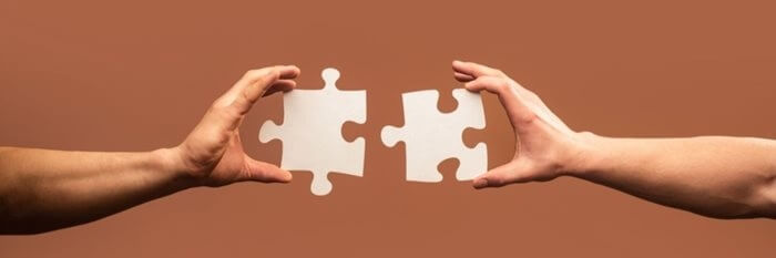 Close up two hands connecting jigsaw pieces. Teamwork concept.