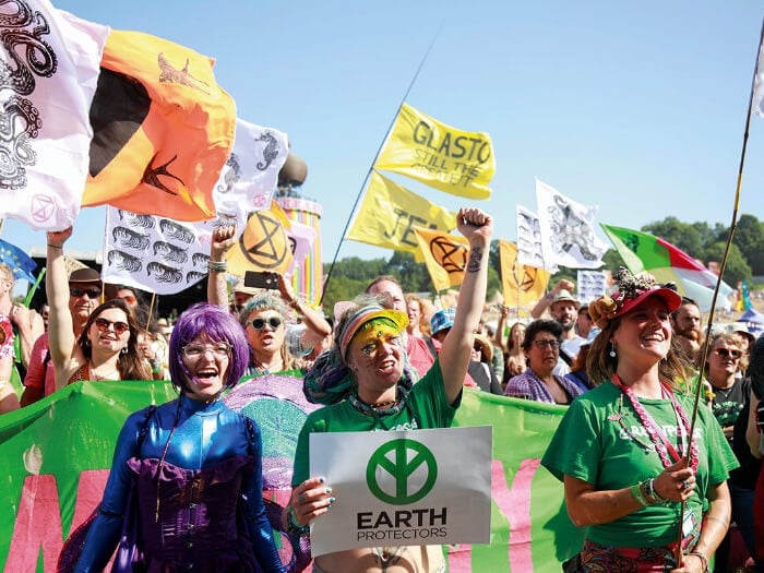 Brightly dressed protestors raise banners with Extinction Rebellion symbols and words such as 