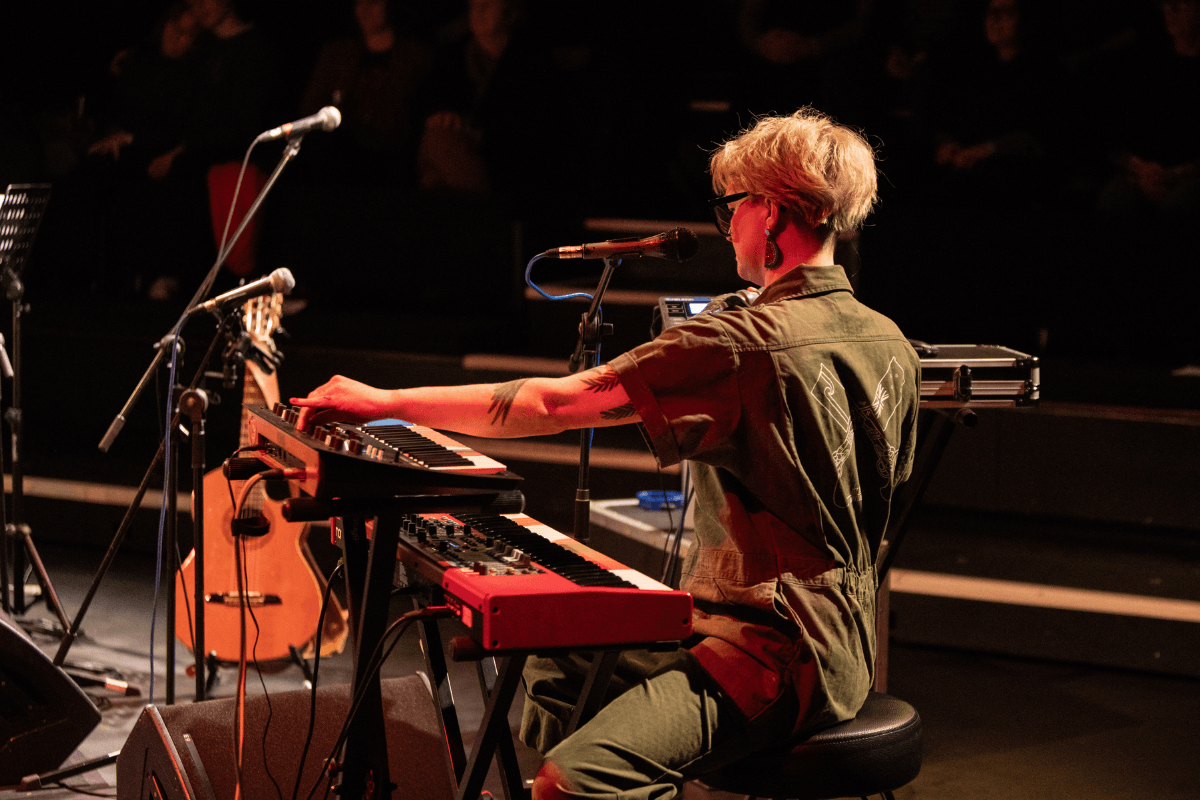 Bridget playing keys and synth on a festival stage.