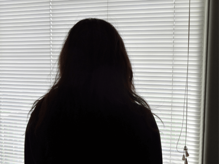 Anonymous women in silhouette against a window blind.
