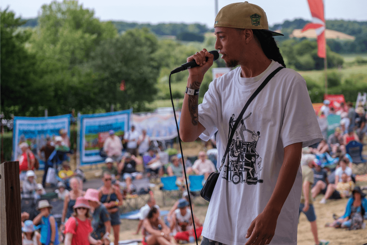 Wrapper, Isaiah Dreads, performing on stage at Tolpuddle wearing the MU and LMHR limited edition t-shirt.