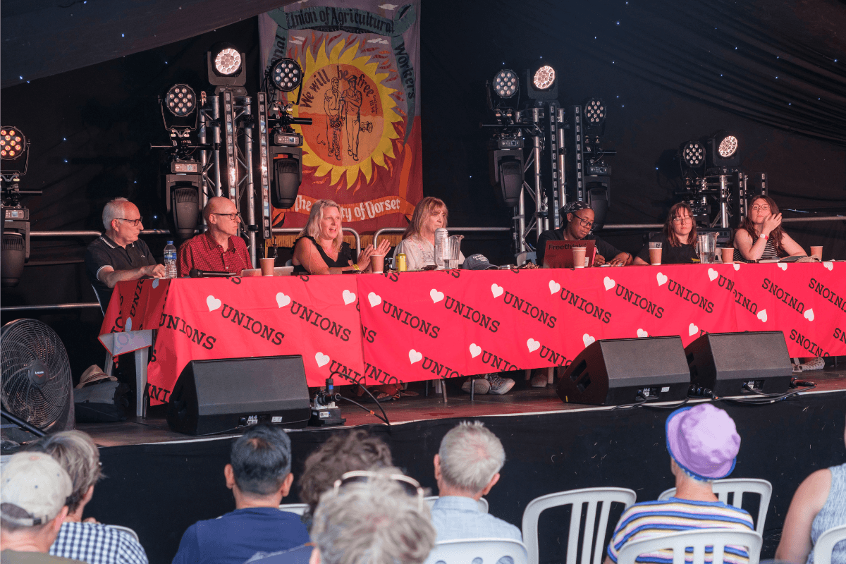 Naomi speaking on a panel, on a stage at Tolpuddle Festival 2026.