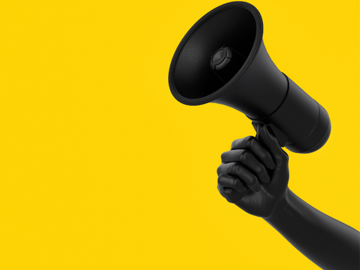 Black hand holding a black megaphone against a bright yellow background.