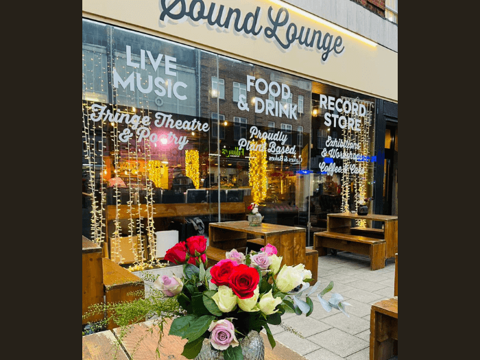 Exterior of the Sound Lounge, with lights and signs on the windows saying Live Music and Record Store.