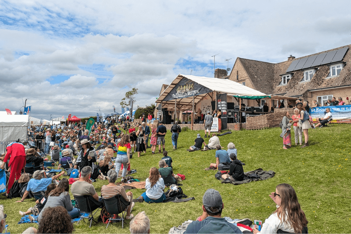 Crowd in front of the main Tolpuddle stage, with tents and stalls in the background.