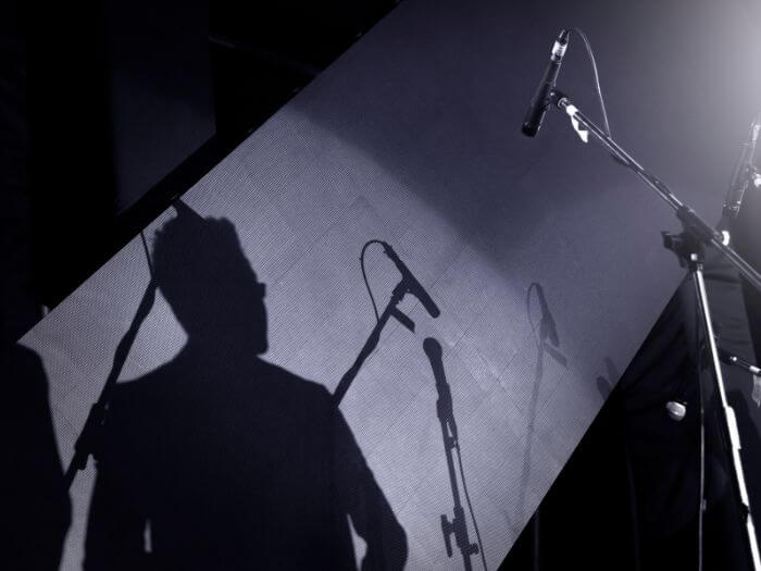 shadow of a musician on stage with microphones