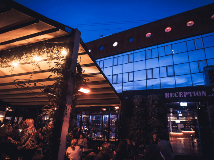 The hotel courtyard in the evening with people sitting around tables decorated with fairy lights.