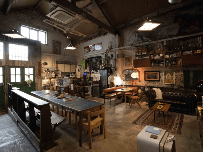 Inside of the venue, showing exposed brick walls and floor, mix and match furnitre and mirrors with low lights creating a cosy feel.