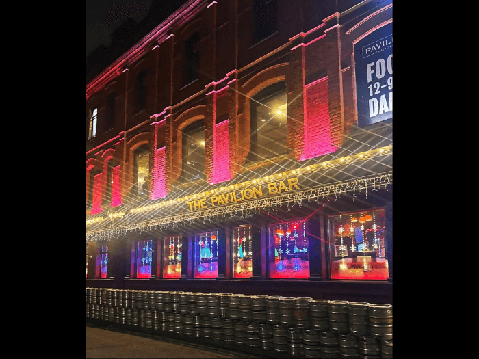 Lit up exterior of the venue from the street in the eveing.