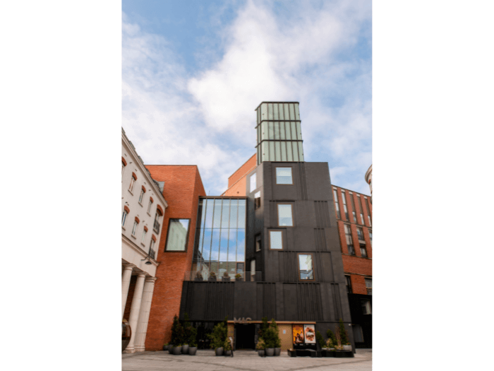 Exterior of the venue, a modern building with a blavk front and large glass windows.