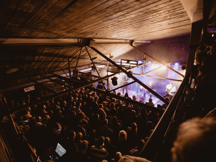 Inside of the venue, view from the balcony looking down at the stage and audience below.