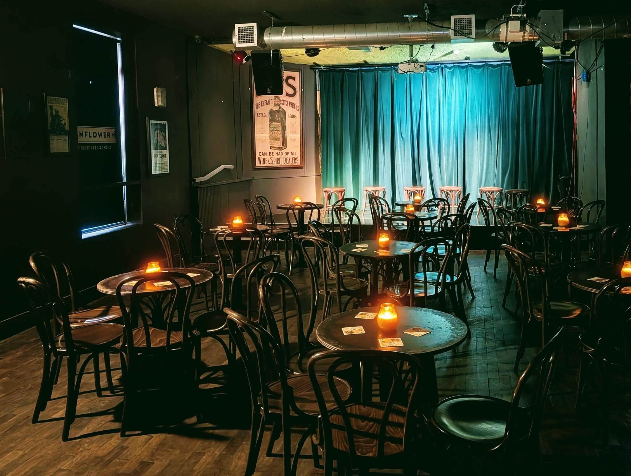 Inside of the venue. Tables and chairs lit with candles in front of a small stage.
