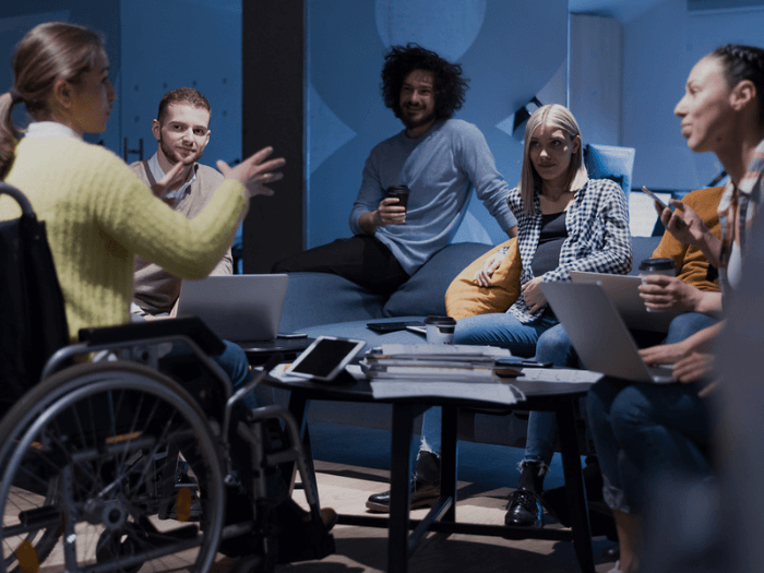 Young woman in wheelchair holding a meeting to some colleagues in an informal setting at work.