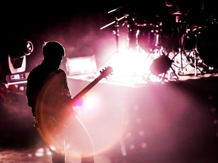 A man with a guitar on stage in red light.