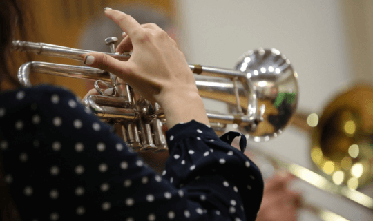 A woman holding a wind instrument.