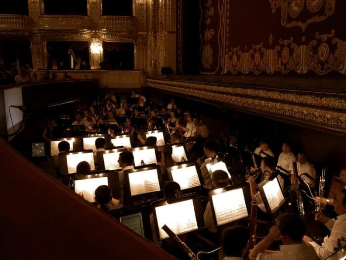 Full orchestra pit at a theatre with the stage curtain down.
