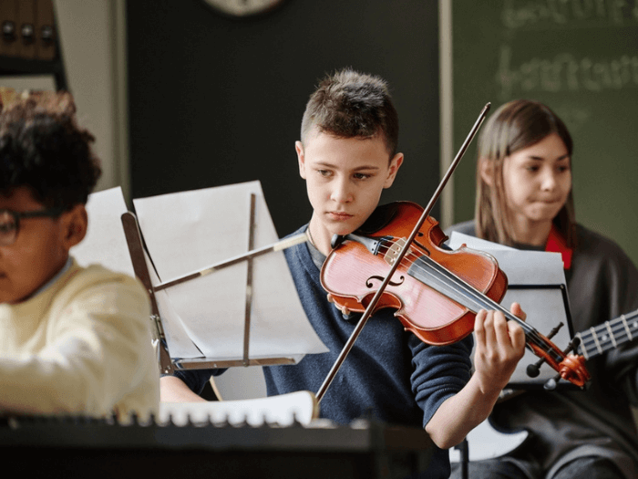 A young boy reading sheet music and playing violin.