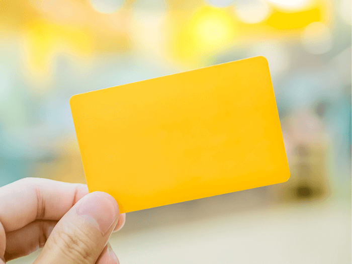 A hand holding a yellow membership card.