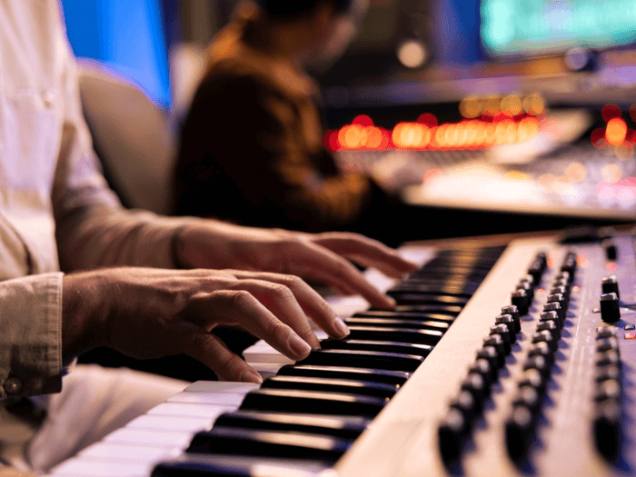 A musician playing a keyboard in a recording studio.