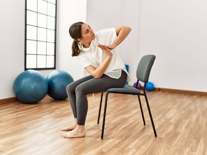 Young woman sat on a chair in a studio doing yoga.