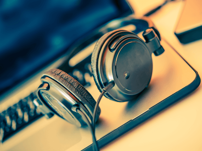 A pair of headphones on a table connected to a laptop,