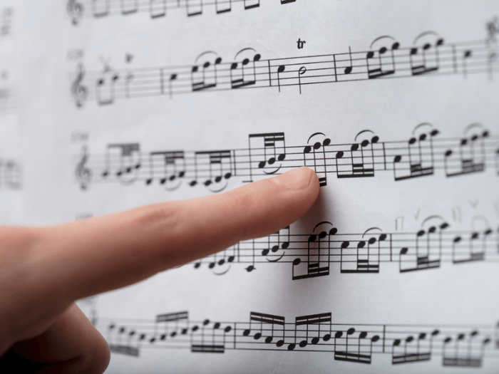 A finger following a music score on a sheet of paper.