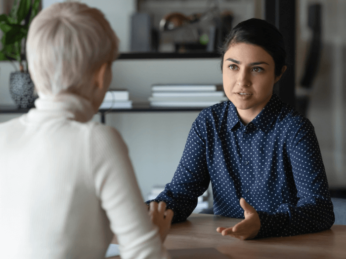 Two women sitting face to face at a table and having a conversation.