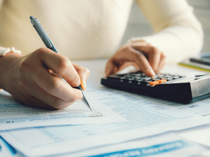 A woman with a calculator filling out tax forms.