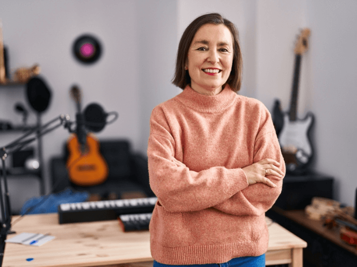 A middle aged woman standing with a selection of music instruments.