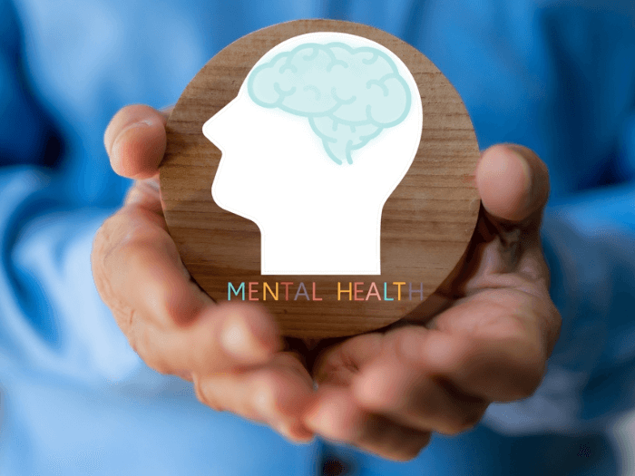 Two hands holding a wooden circular block with a picture of a brain to symbolise mental health.