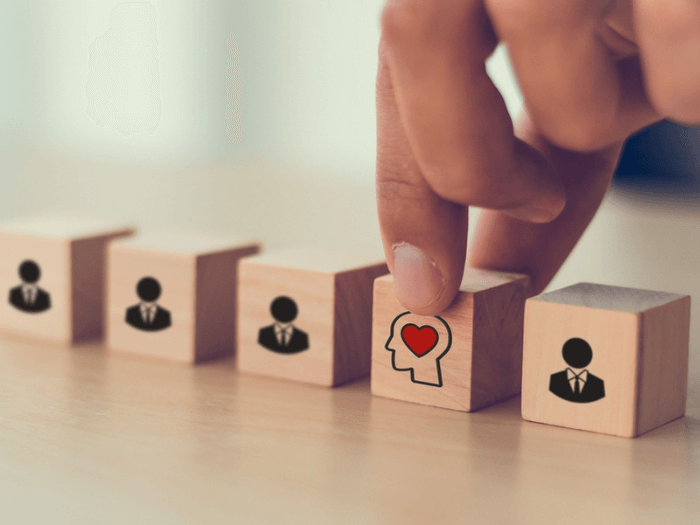 A hand with wooden blocks with illustrations on them representing mental health.