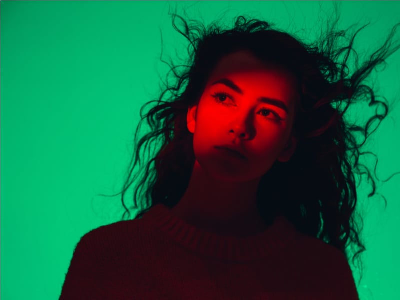 Young woman on green background in red spotlight