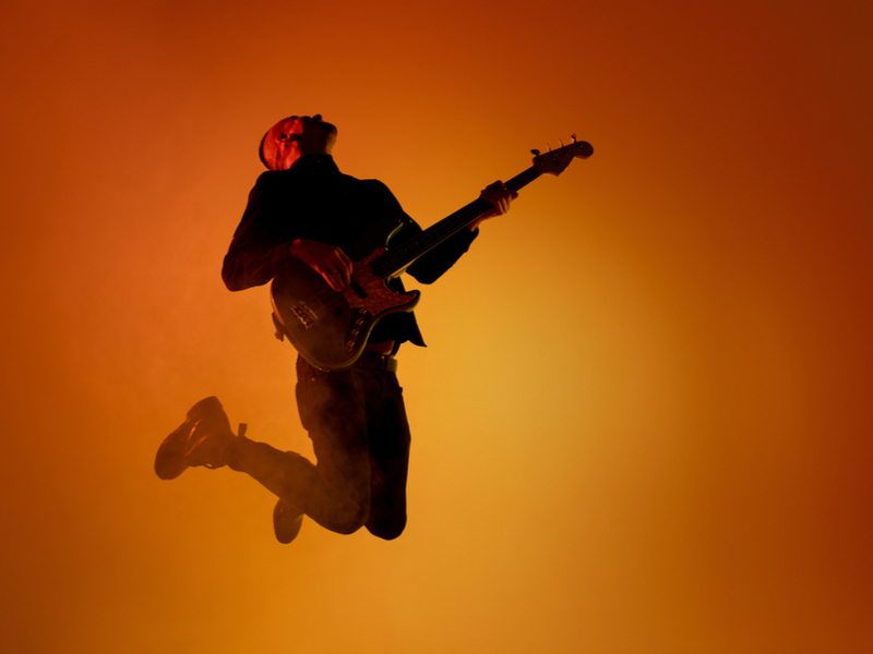 Silhouette of young male guitarist jumping