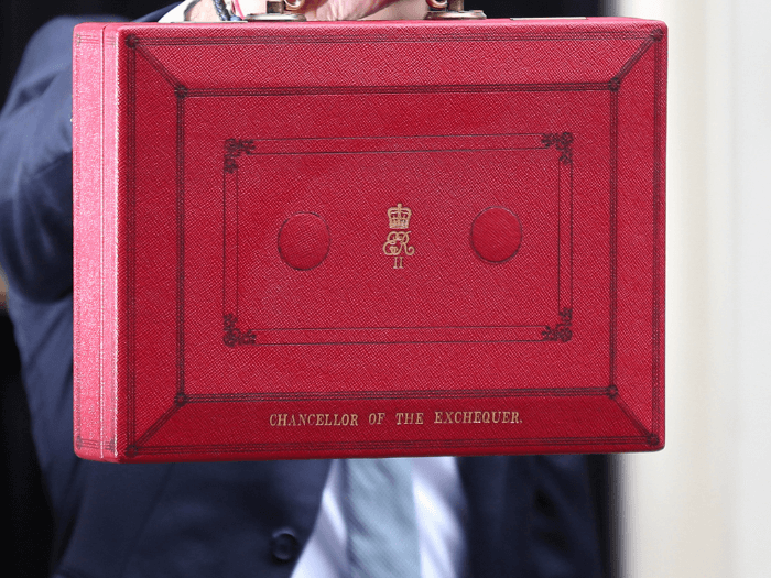 Hand holding the red dispatch box outside Downing Street ahead of revealing the budget in the House of Commons.