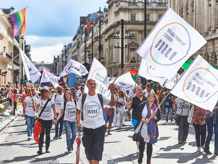 Musicians' Union staff and members holding Pride flags at a Pride march.