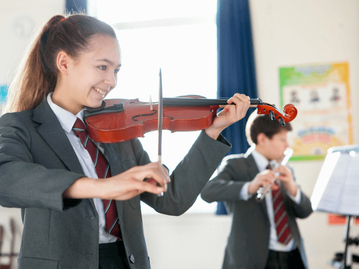A student in a classroom playing violin as part of a music workshop.