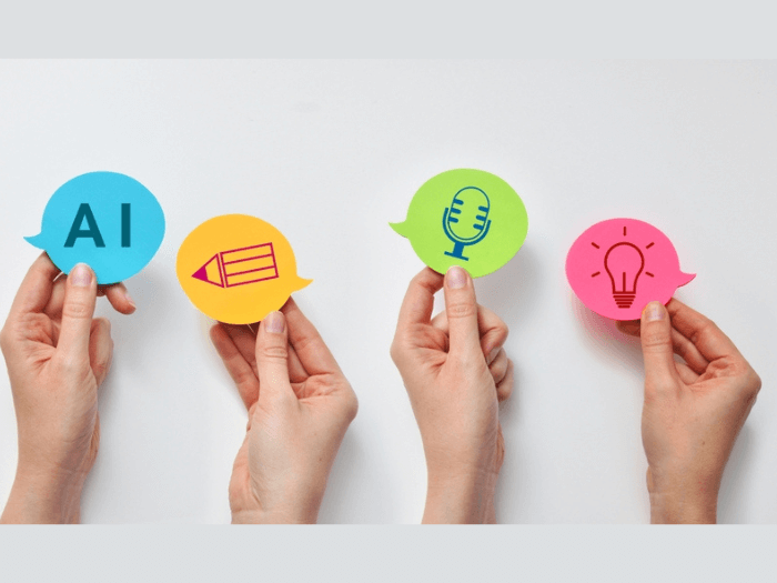 Four hands each holding paper speech bubbles in different colours, the first says 'AI' and the others are images of a pencil, microphone and lightbulb.