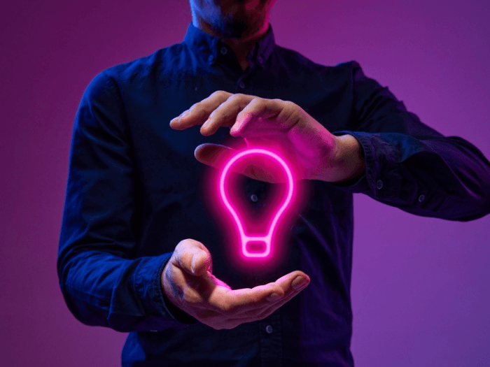 Neon colored light bulb graphic between two hands.