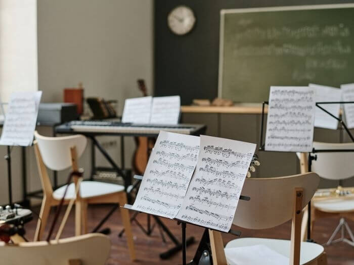 Sheet music on music stand in empty modern classroom.