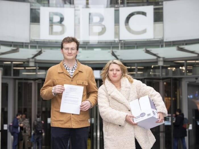 Naomi Pohl and Jack Apperley holding the Singers petition outside of the BBC offices.