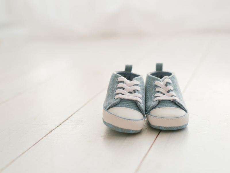 A pair of pale blue denim shoes on painted white floorboards.