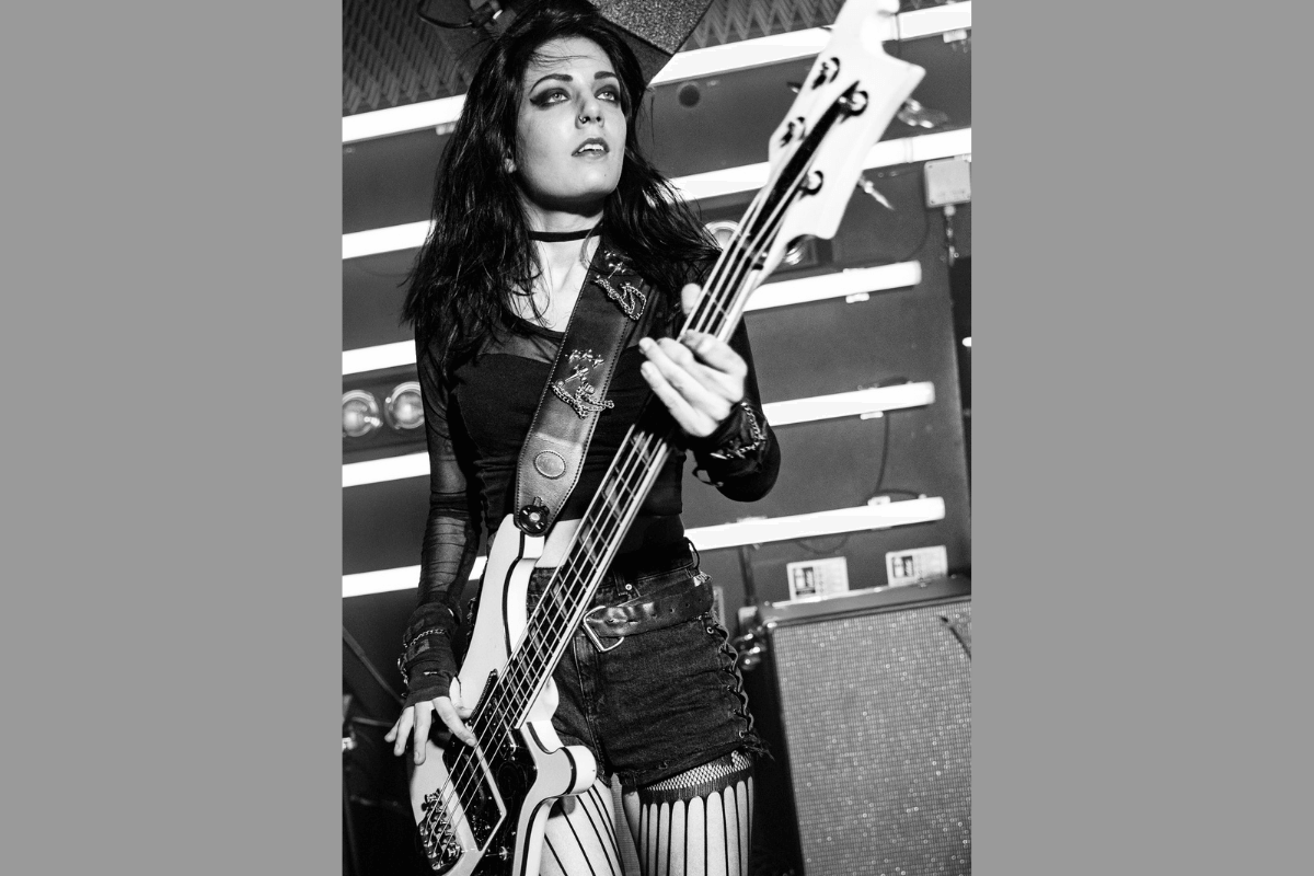 Becky Baldwin on stage playing bass, in black and white.