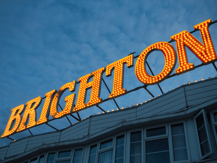 Large up close 'Brighton' sign from Brighton Pier against a blue sky.
